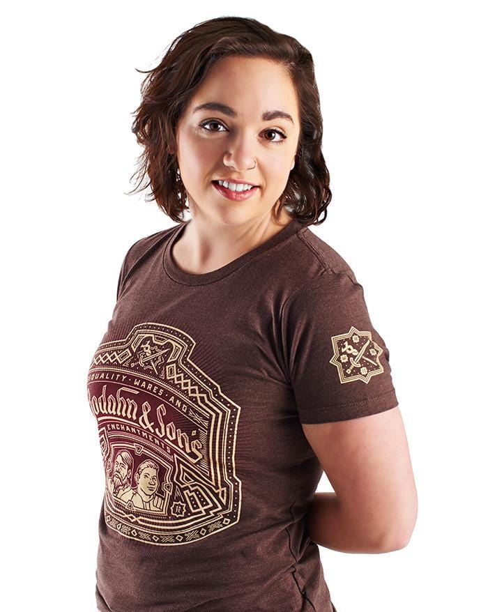 Bodahn and Sons shirt, featuring an image of the father-son duo with a Dwarven design around it, and the name of their shop. Worn by a model and angled at a 3/4 view to show off the sleeve print of a sword and staff.