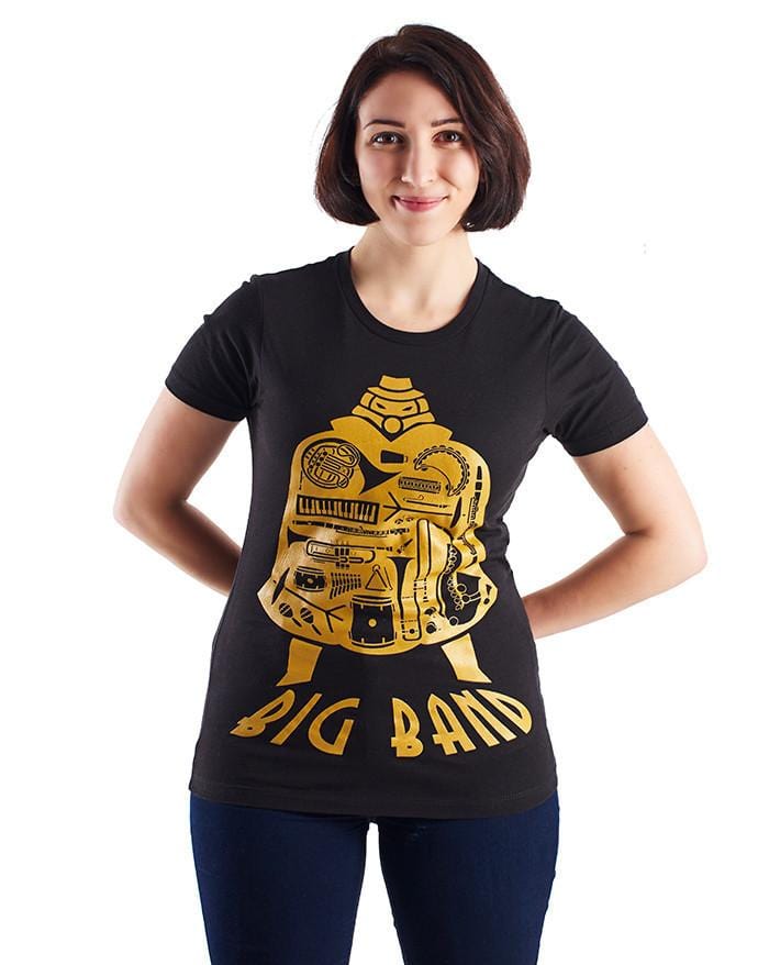Image of the Big Band shirt, which features the SG character, his silhouette filled with the images of various musical images, and the name "Big Band" along the bottom of his image. It is shown being worn by a woman in a women's size to show the alternate cut of the shirt.