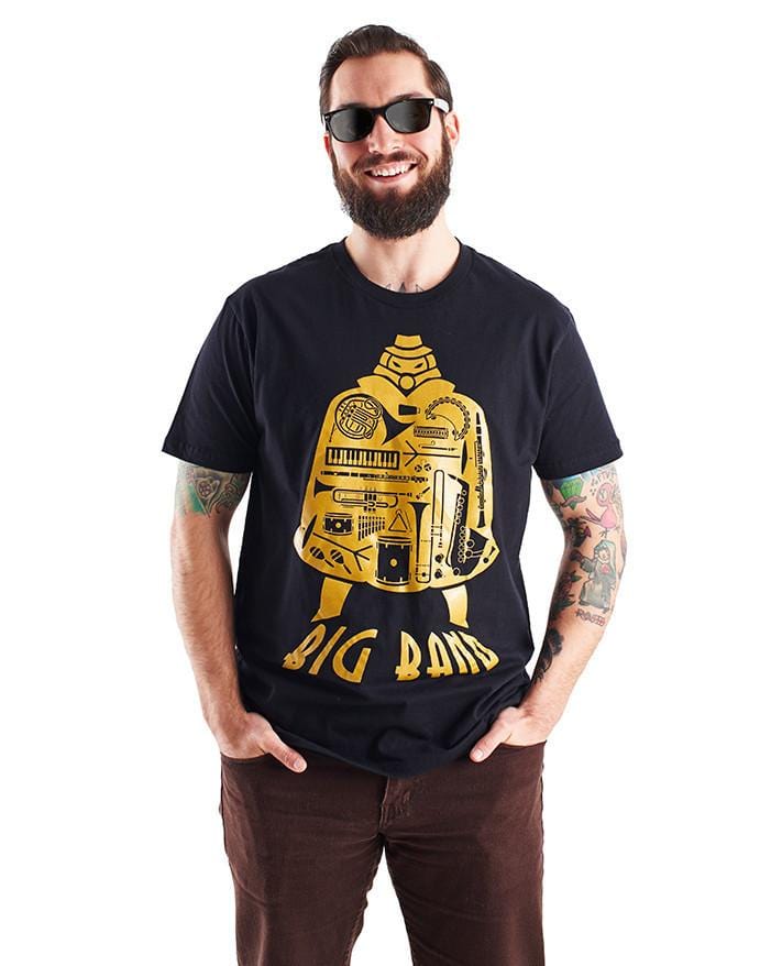 Image of the Big Band shirt, which features the SG character, his silhouette filled with the images of various musical images, and the name "Big Band" along the bottom of his image. It is shown being worn by a smiling model with a beard.